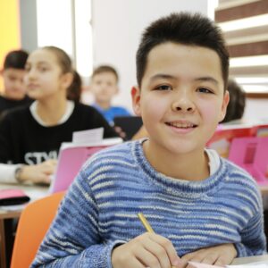 boy in blue and white striped long sleeve shirt holding pencil